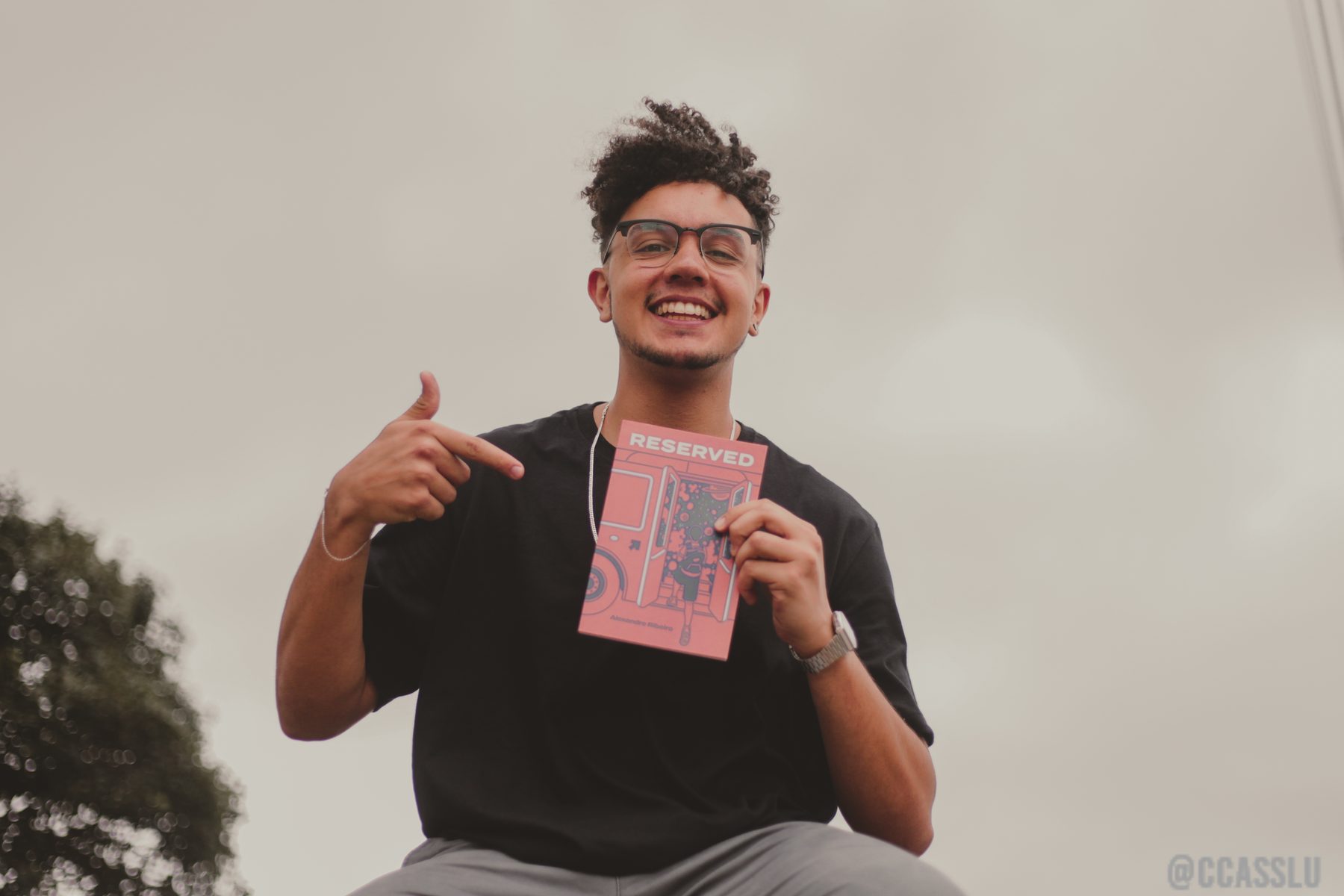 Alexandre Ribeiro lächelt und hält das Buch Reservado.